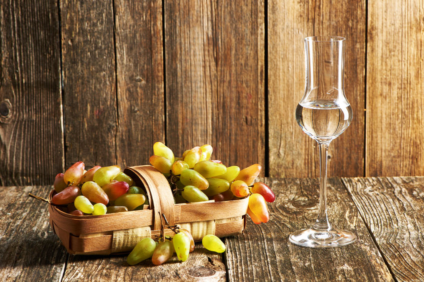 Fresh grapes and glass of grappa on old wooden table - ClipDealer - haveseen